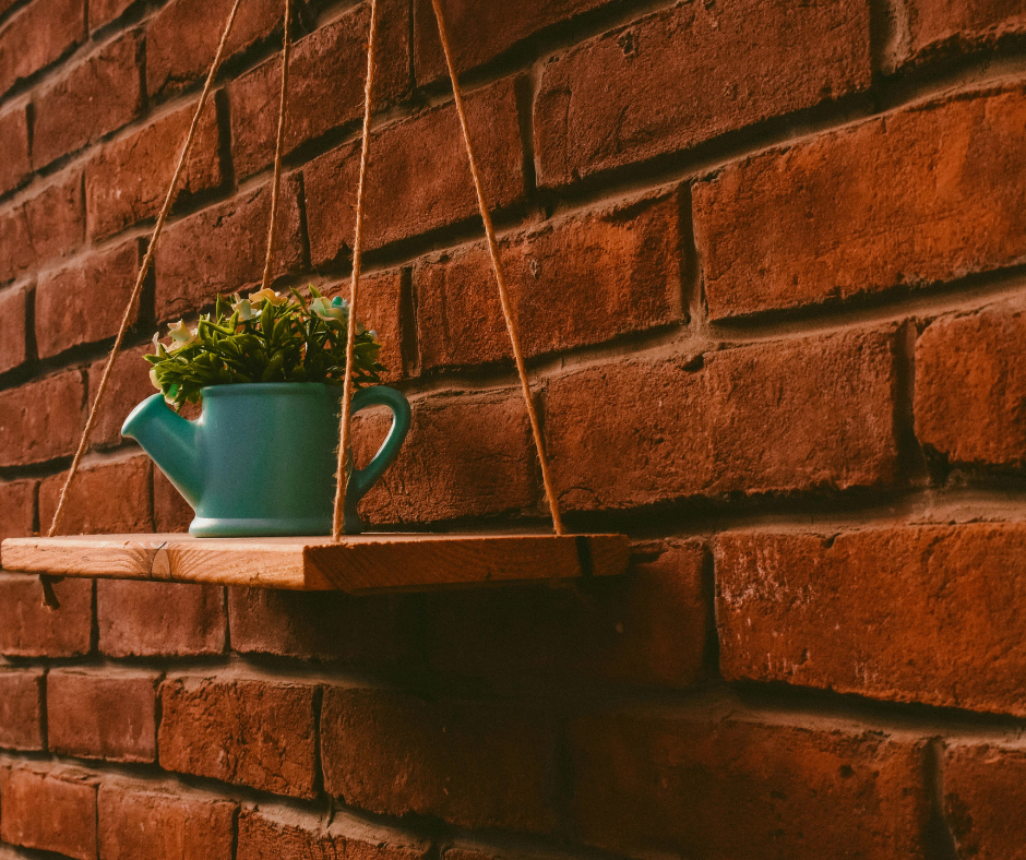Estante suspensa rústica decorando uma parede com livros e plantas